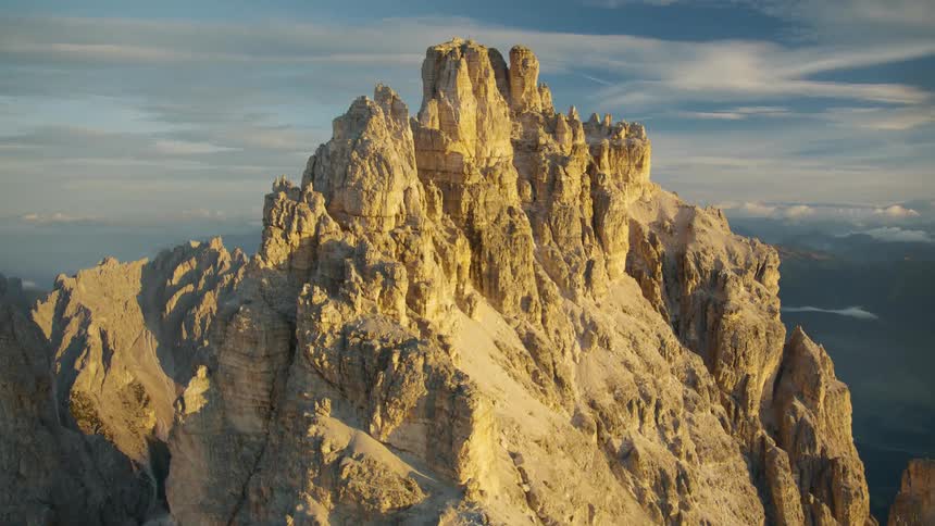 An aerial view of a mountain range and cliffs above the cloud level