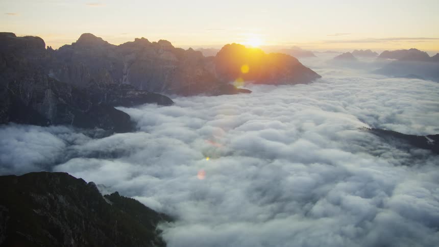 Aerial of a mountain landscape covered by white clouds at dawn