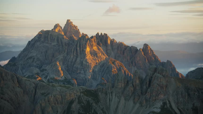An aerial view of a mountain range and cliffs above the cloud level