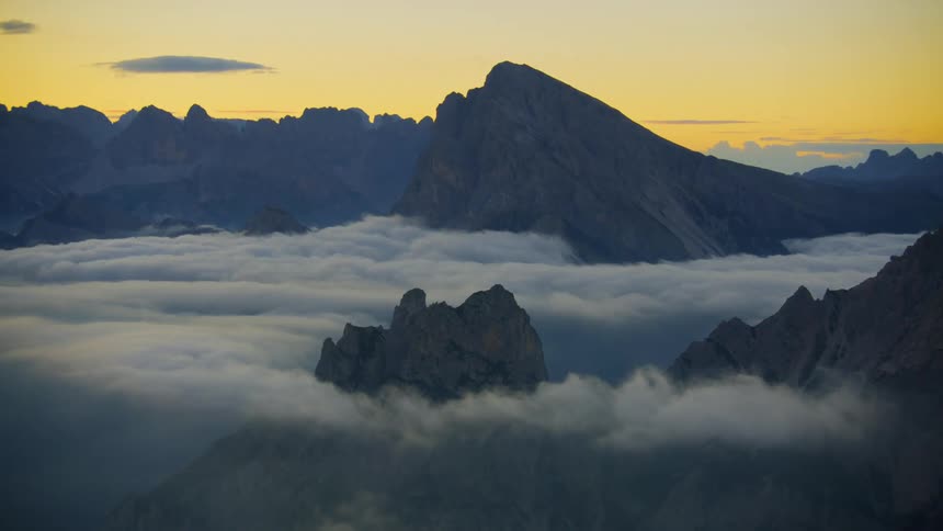 An aerial view of mountains and cliffs above the cloud level at sunrise