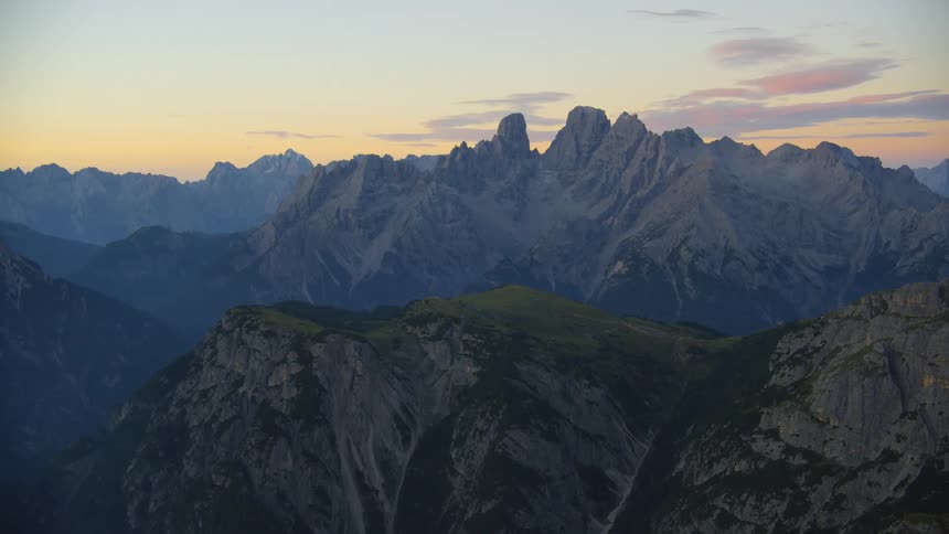 Fog covers mountainous terrain growing denser toward the red horizon