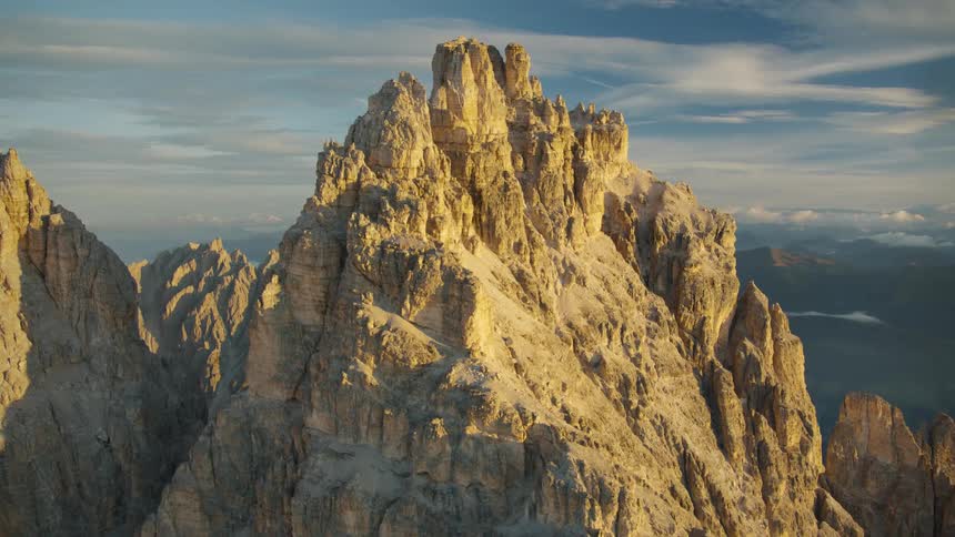 Pole sits on peak of jagged mountain towering over foggy valley