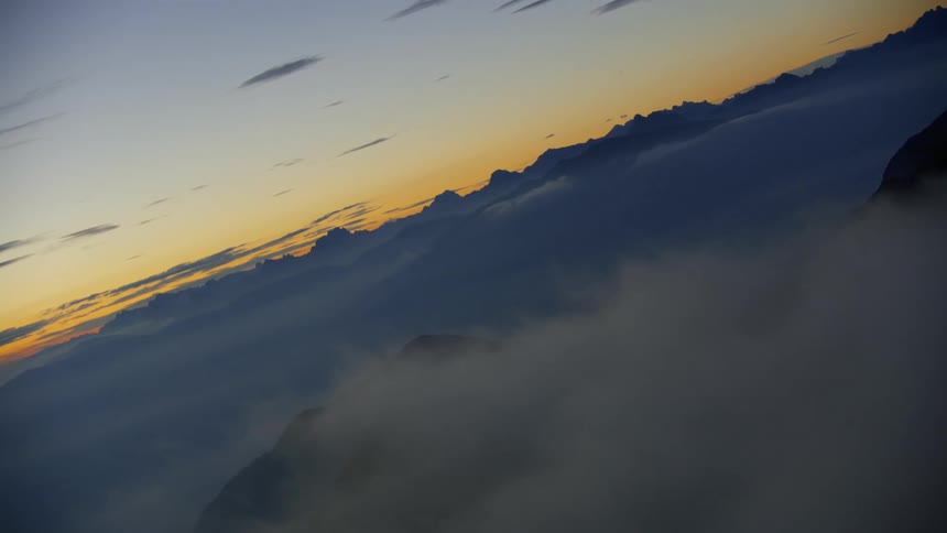 Landscape of mountains above the cloud level with an orange dawn sky