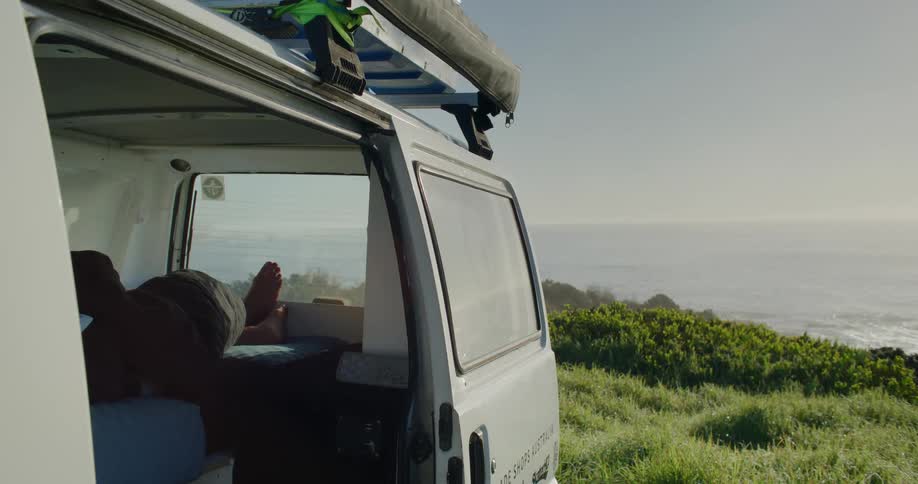 A person is sleeping in the van by the shore