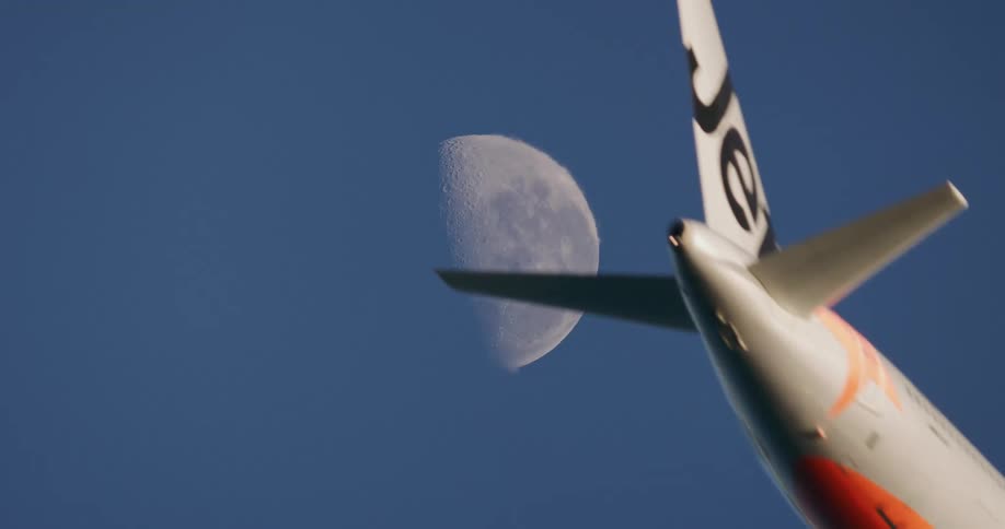 The moon shines in the sky as a plane flies overhead