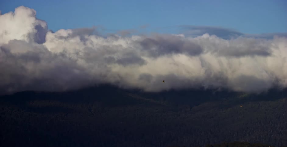 Sunlight shines on clouds as they roll across the sky and over the land