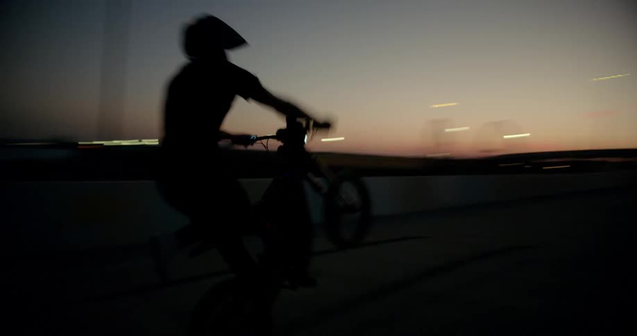 A man performing a wheelie on a motorcycle at night