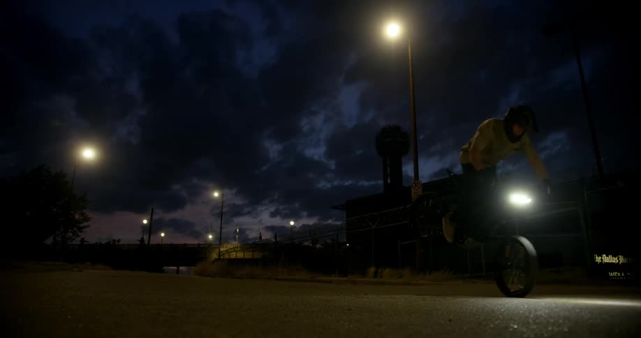 Man riding a motorcycle pulls its brake to make a quick stop at night