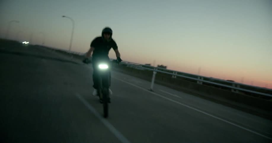 A man in a helmet is driving his motorcycle back and forth on an empty street