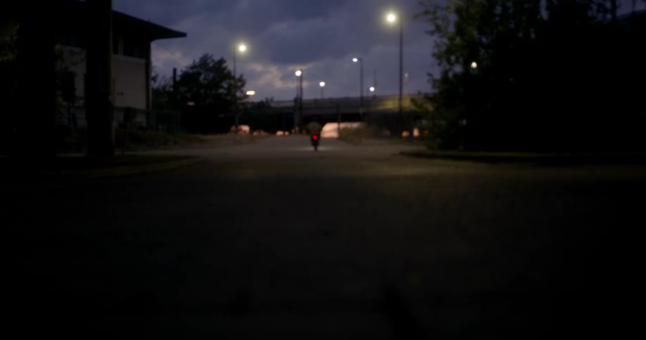 A man in a helmet driving a motorcycle in the middle of the street at night
