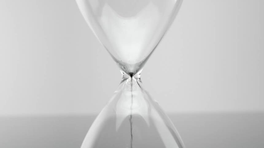 Black sand falling quickly into the hourglass