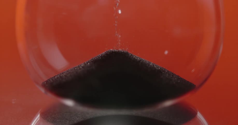 An hourglass where grains of sand are falling into the compartment below