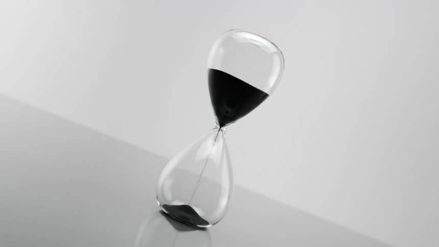 A view of an hourglass with black sand falling