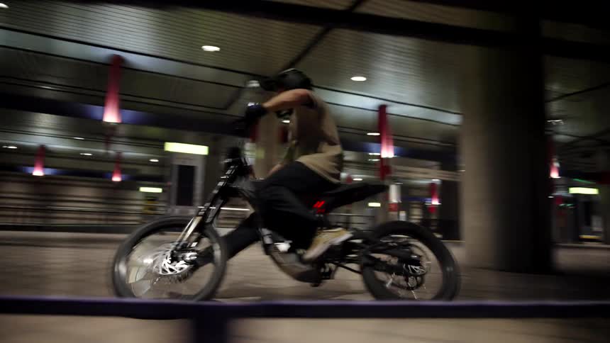 A teenage boy is riding his bicycle through a parking garage