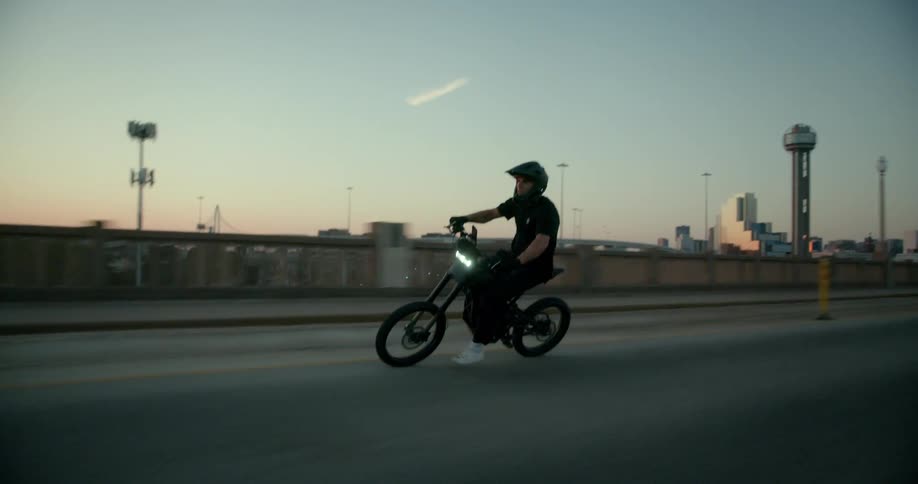 A man in a helmet is driving a motorcycle sideways on a street