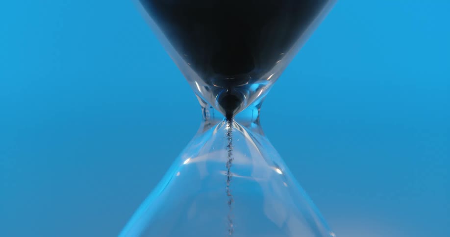 Hourglass with black sand in motion against a blue background