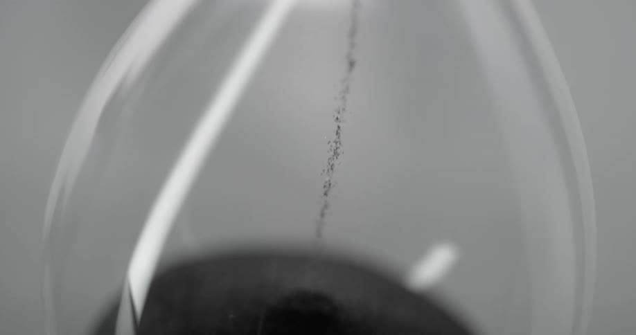 An hourglass with grains of sand falling from the top