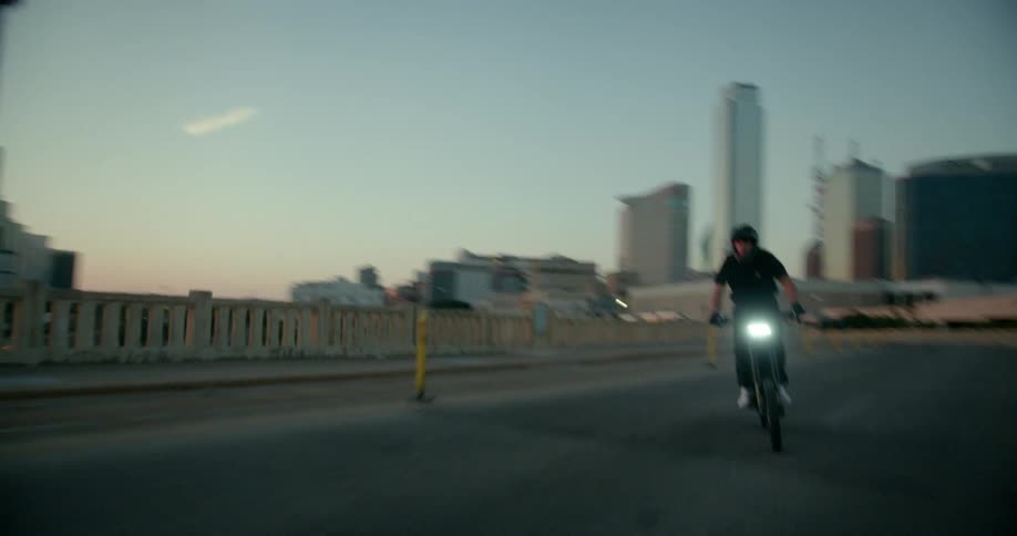 Man rides a motorcycle on a tarred road in a city at sunset