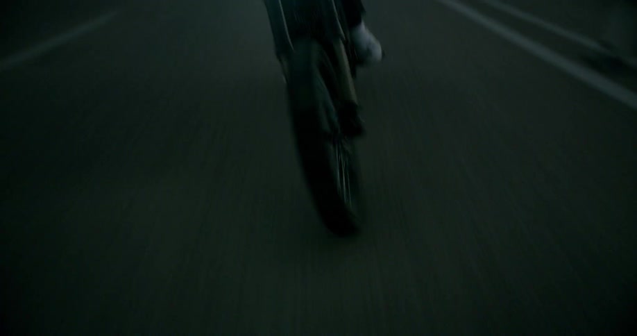 A man is driving a motorcycle in the evening in the middle of the road swerving left and right