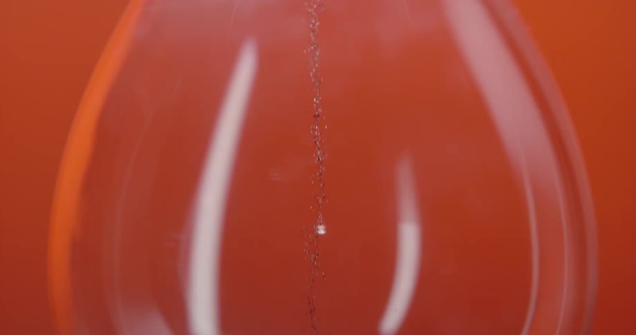 A glass hourglass on an orange table