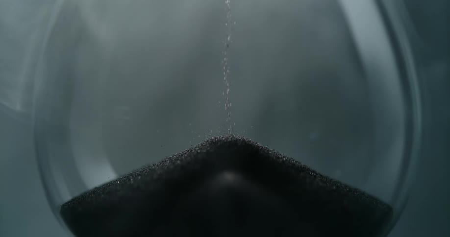 Closeup of sand dropping inside the hourglass