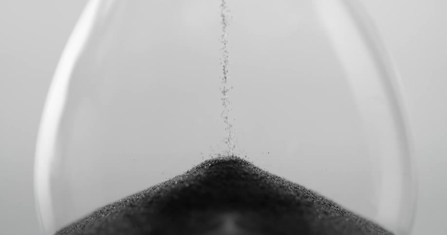A transparent hourglass with black sand falling down