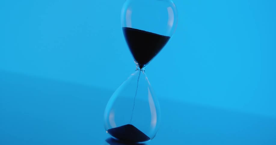 Hourglass with dripping sand placed on the floor indoor
