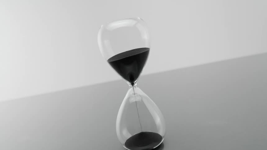 Sand flows through the center of an hourglass as the bottom fills with sand