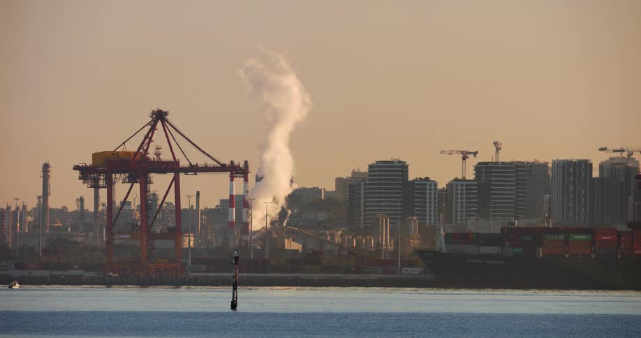A city with many buildings on a coast with cargo ships and industries
