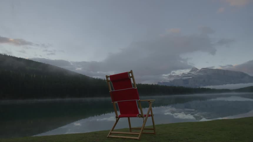 A red chair sits near a lake