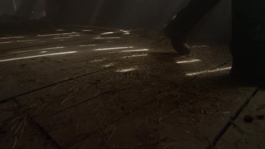 A person is walking in a dark barn