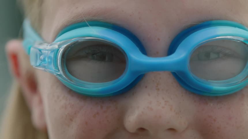 A young girl wearing a swimming googles as she looks excited