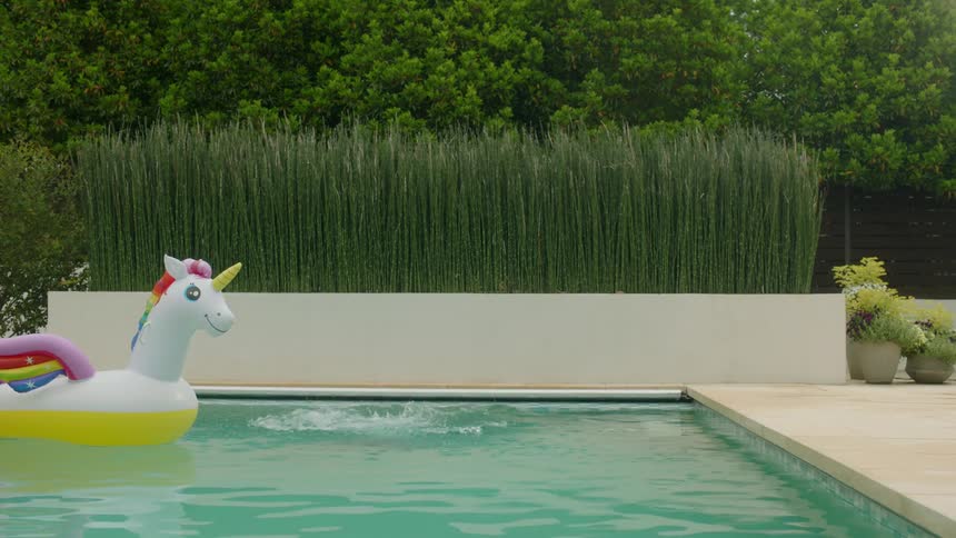 A girl jumping into the pool wearing swimming goggles