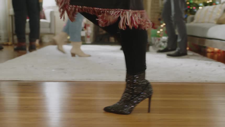 Shiny black boots on the feet of a person walking