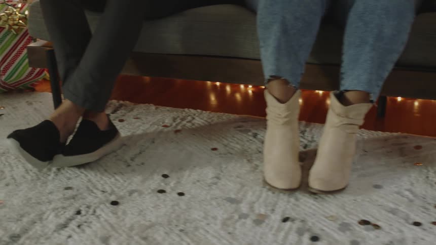 Legs of three people sitting on a couch indoor