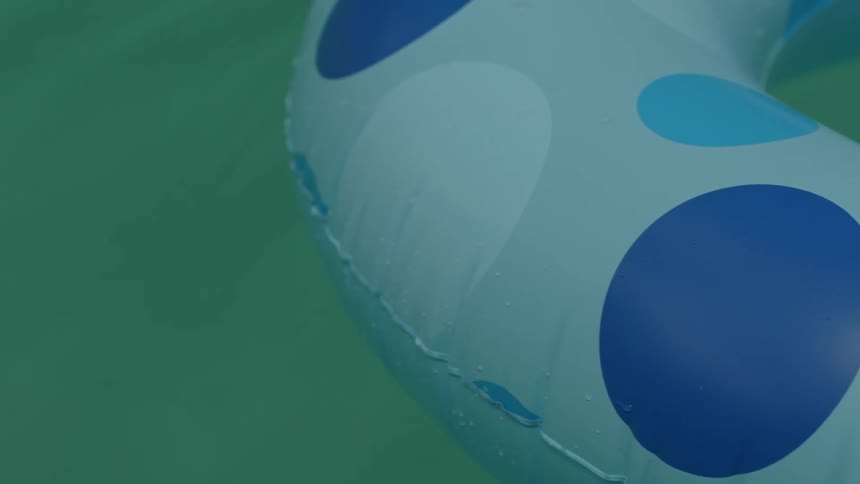 A closeup shot of a paleblue inner tube floating on some green water like in a pool the innertube has dark medium light blue circles decorating it