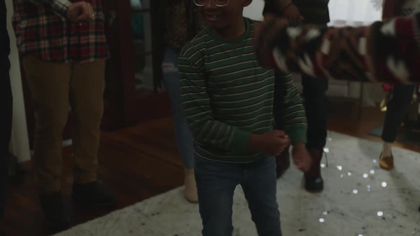 A preteen boy is dancing with boots on and several people around him are celebrating