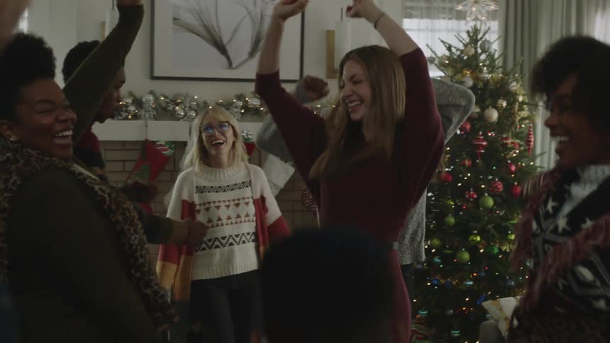 Friends inside a houses living room all happily dancing during the christmas season