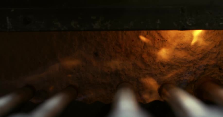 A fire inside a hole with some metal pipes on top