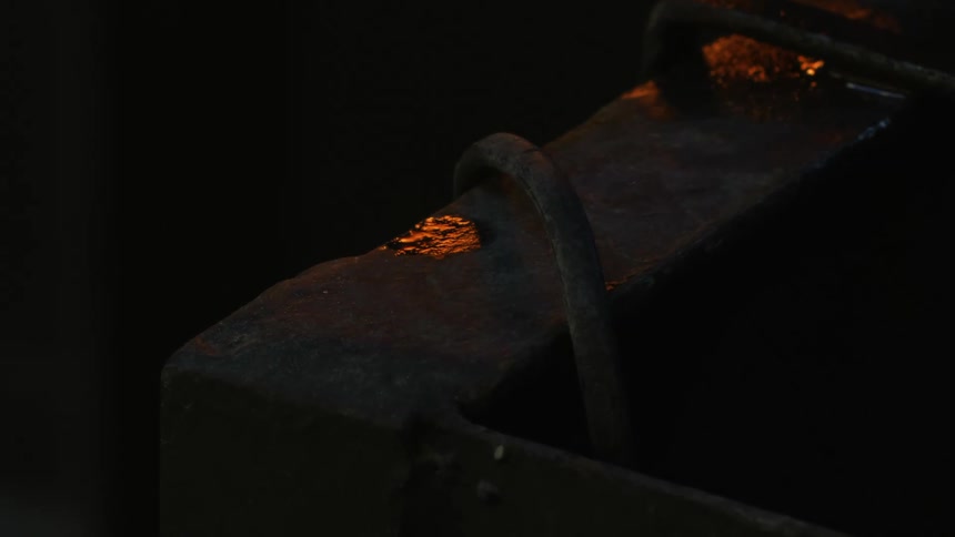 Metal pieces over an anvil in a dimly lit forge