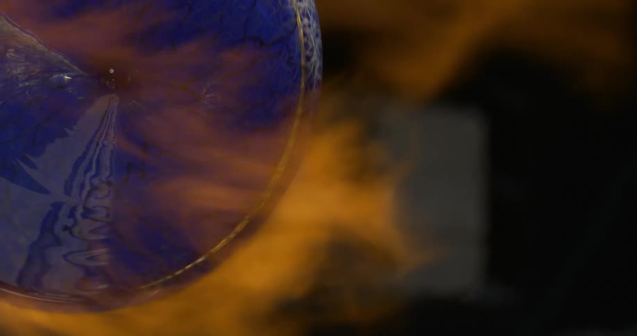 Piece of colored glass being turned under flames