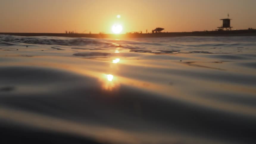 A sea view with waves in motion and the sunset on the horizon