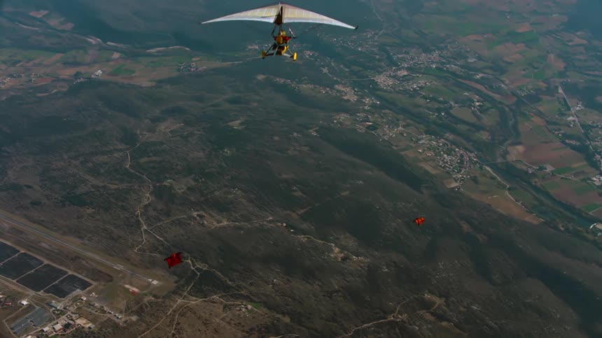 Two people flying hang gliders and others doing wingsuits in the heights