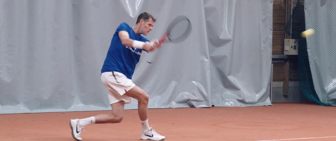 A man playing tennis and smashing the ball with the racket