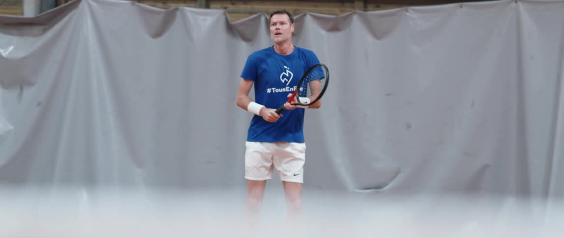 Tennis players returns a ball with his racket