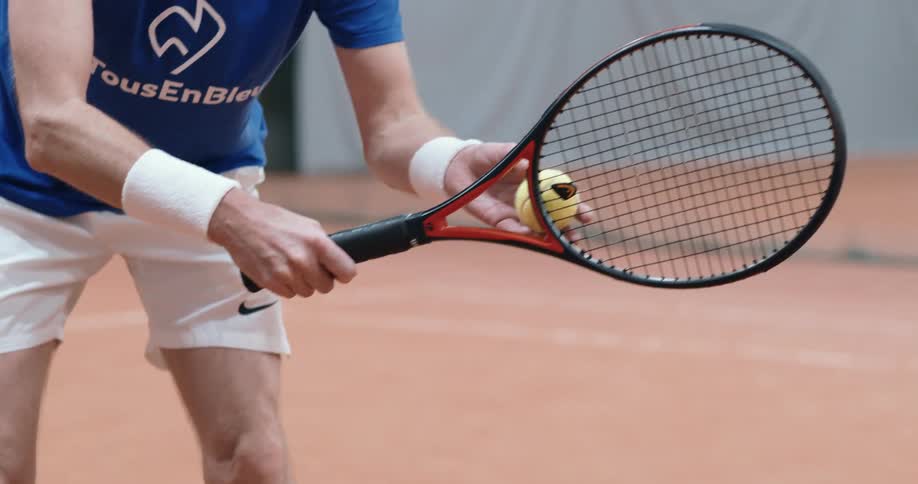 Tennis player serves a ball on an indoors court