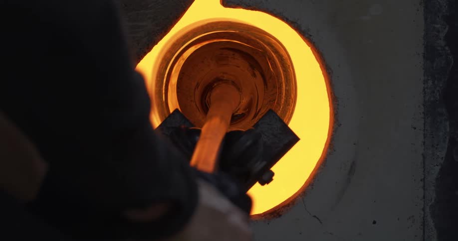 Human hands producing glass in a furnace