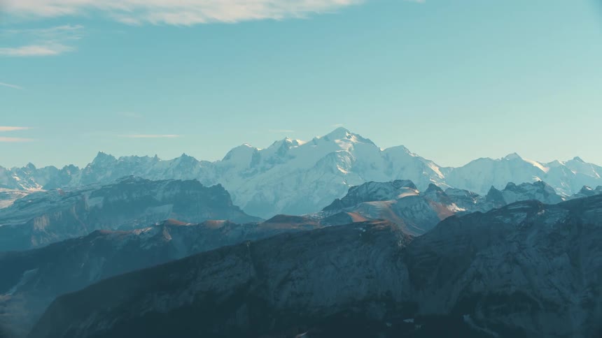 A mountainous region with a huge mountain in the background with a snowcovered peak