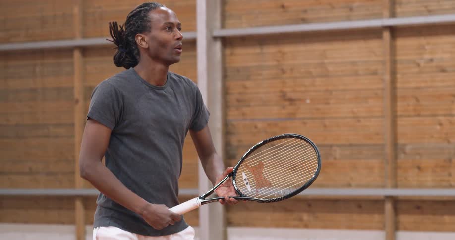 Man playing tennis at midday hits the ball with the racket