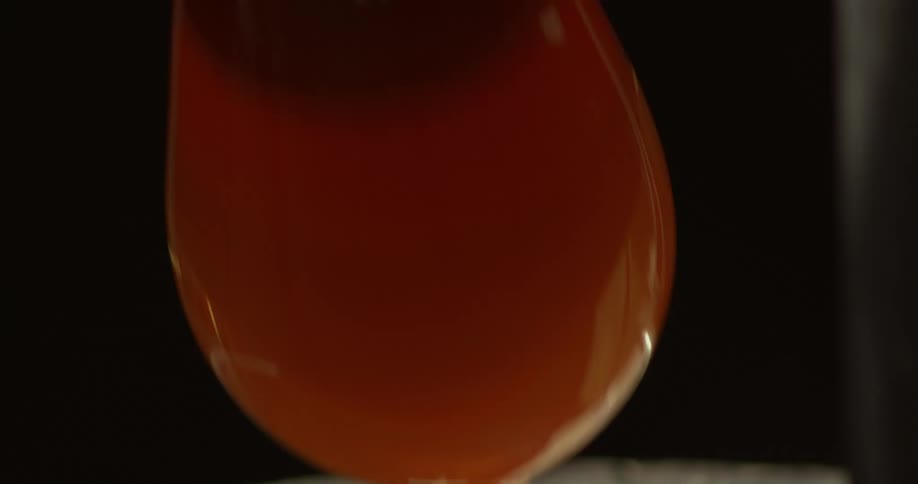 A red hot piece of glass is submerged on a thick orange liquid